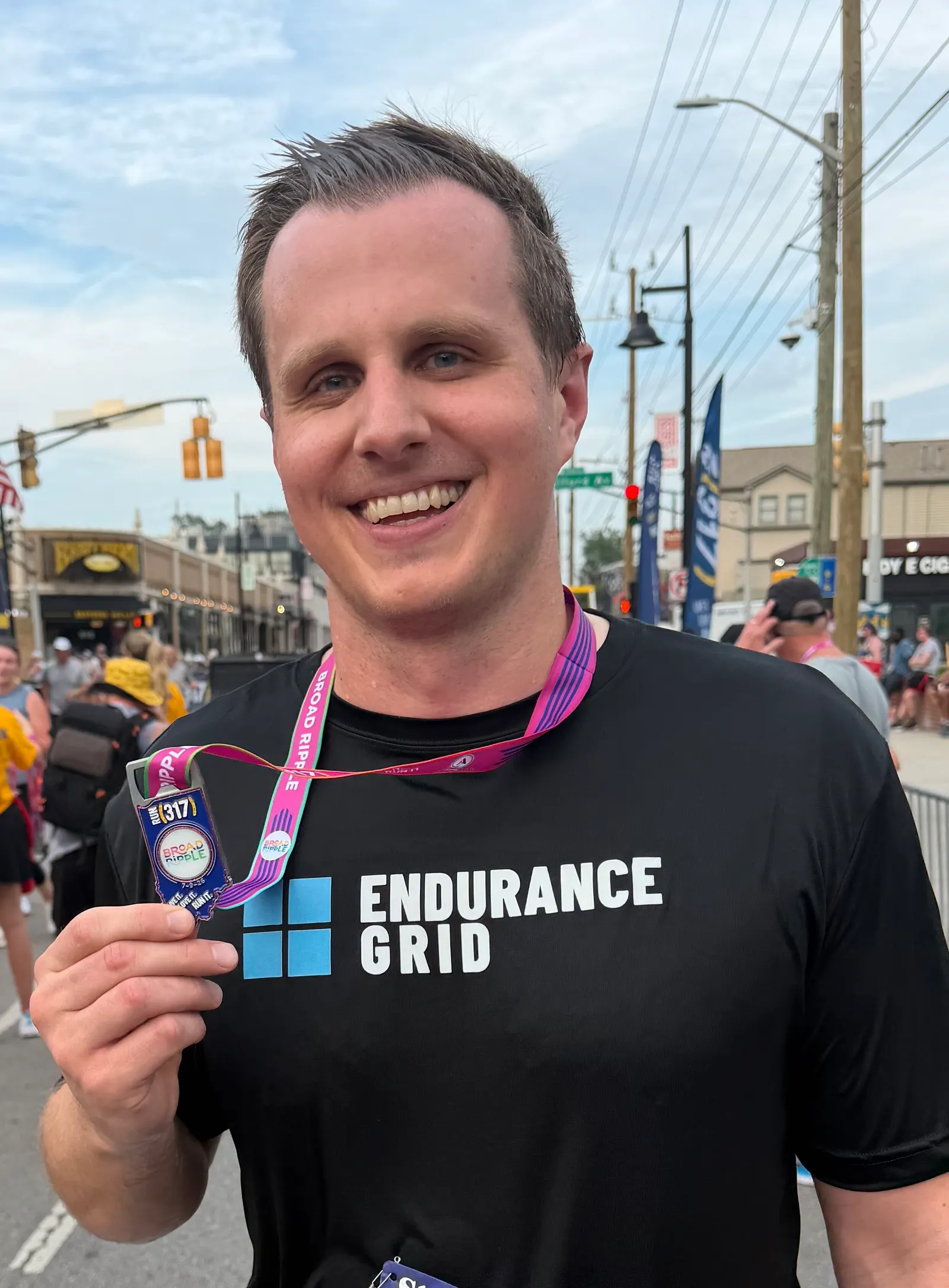 Phil holding up his finisher medal after a race in Broad Ripple